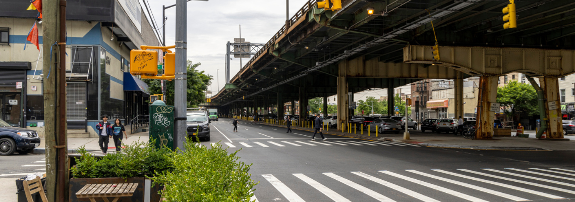 Pedestrians cross the street near an elevated highway in Brooklyn