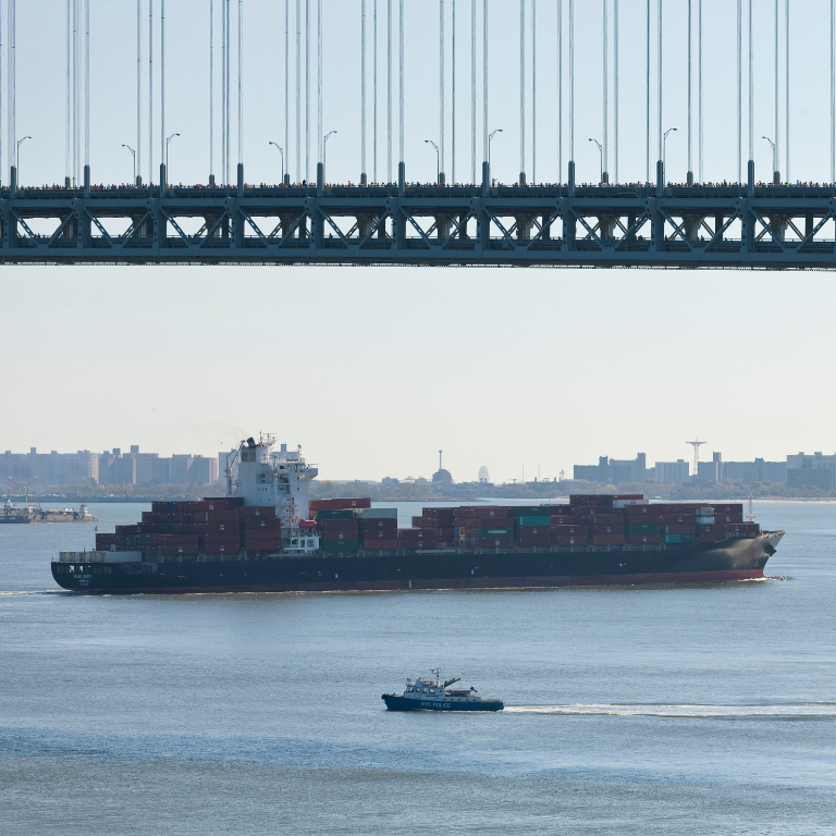 Large barge with containers travels along a NYC waterway
