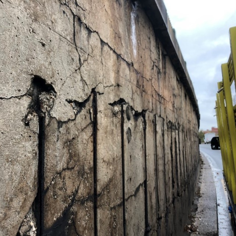 Concrete wall with wear and tear near a roadway