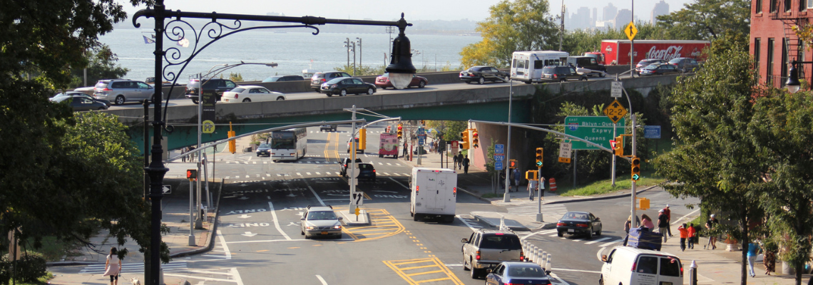 Two-way vehicular traffic travels under an elevated highway in Brooklyn
